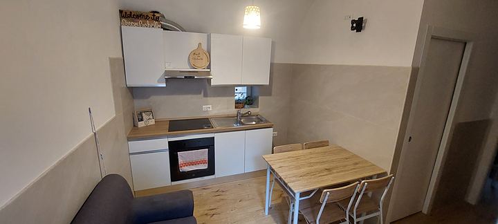 Cucina e zona giorno con tavolo da pranzo e divano